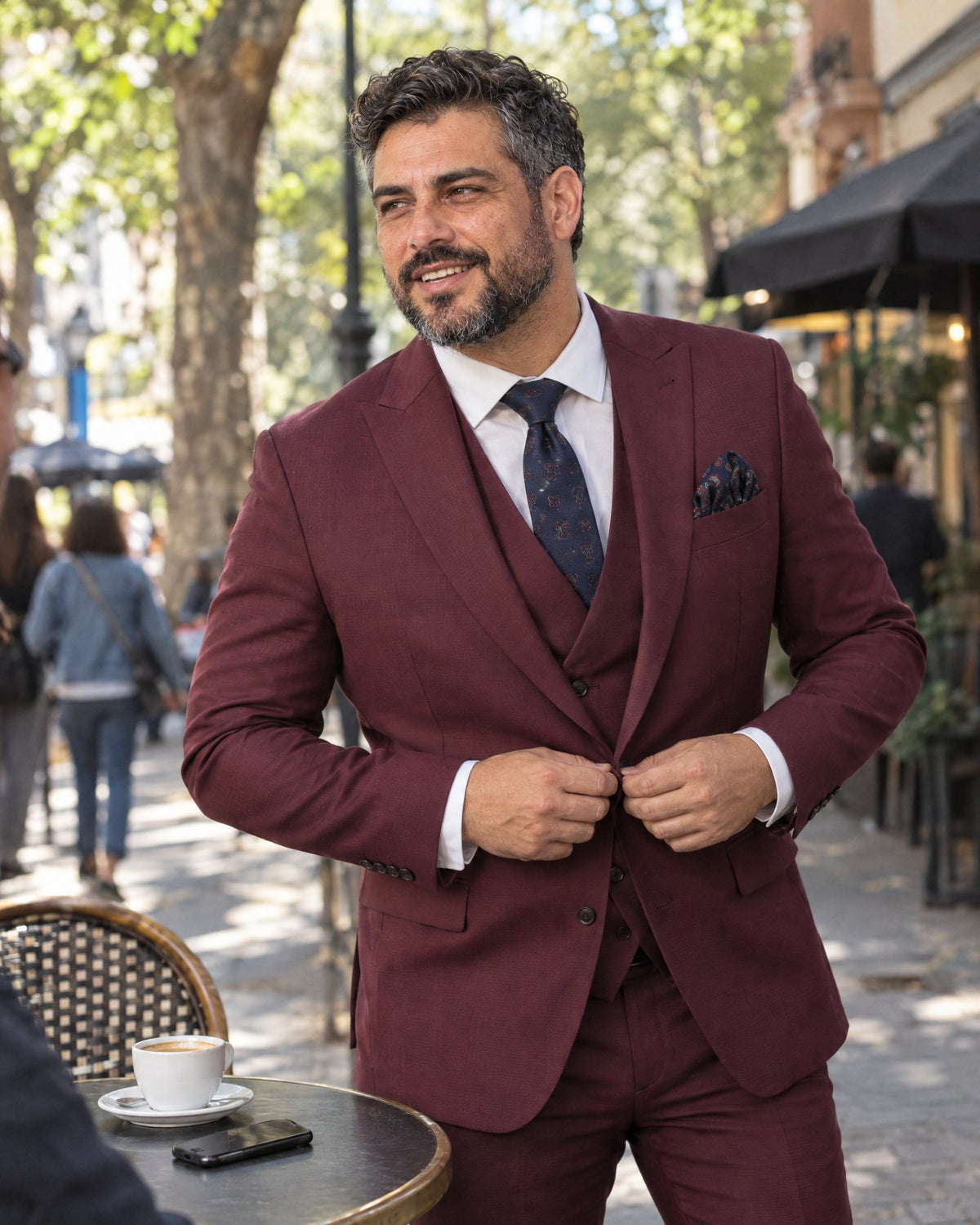 Hombre abotonando su traje Eleganza Borgoña de tres piezas en un café de Santiago